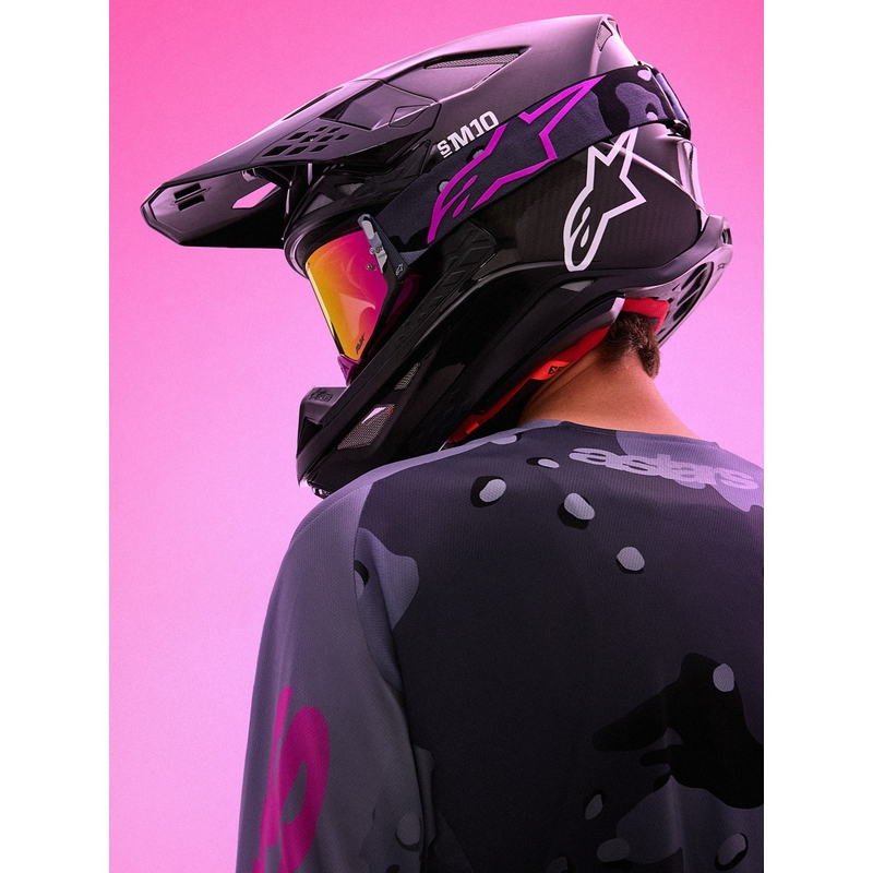 Gafas de motocross Alpinestars Supertech Lone con estampado de camuflaje morado y cristal de plexiglás rosa espejado.